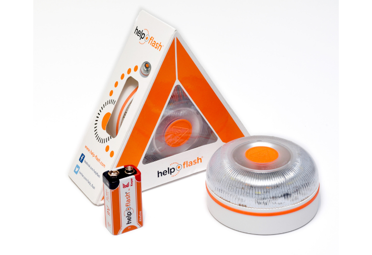 Dispositivo de señalización luminosa Help Flash, con su empaque en forma de triángulo y dos baterías incluidas. El dispositivo es blanco con un botón naranja en el centro, diseñado para situaciones de emergencia en carretera. - Carglass.
