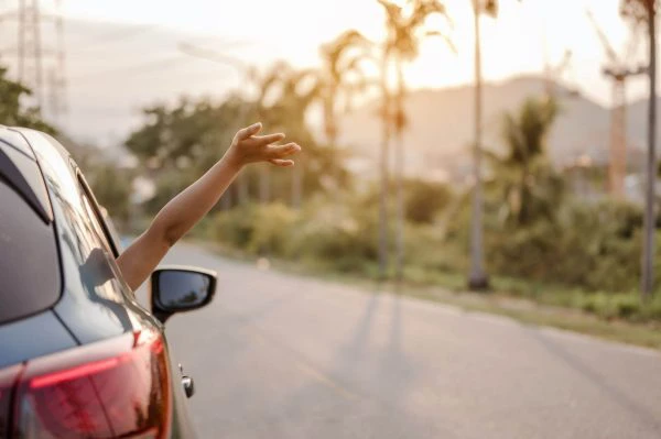 La ventanilla de mi coche no sube ni baja: persona sacando el brazo mientras va en un coche por la carretera