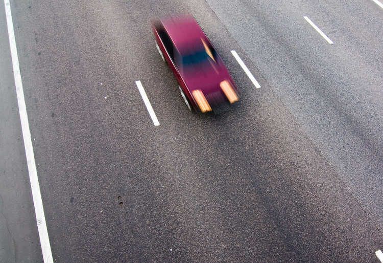 Coche rojo desenfocado en movimiento sobre autopista vacía, ilustrando posibles vibraciones en el coche al conducir a alta velocidad - Carglass.