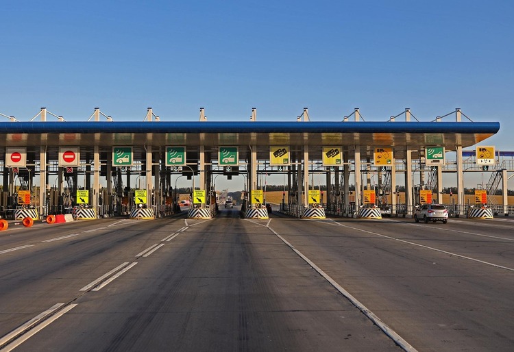 Estación de peaje en Europa con carriles señalizados para vehículos y métodos de pago, destacando señales amarillas y rojas. Cómo pagar peajes en Europa - Carglass.