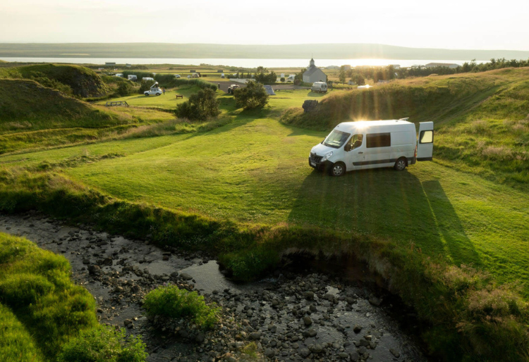 Mejores furgonetas para camperizar: furgoneta camperizada aparcada en medio de un campo verde