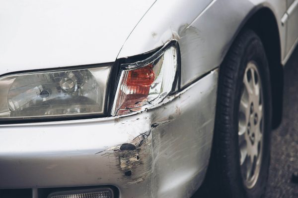 Se puede poner un plástico en el faro del coche roto: coche gris con el faro roto tras un accidente