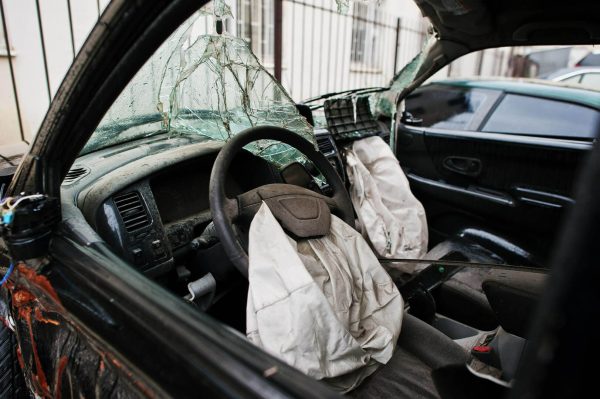 Seguridad activa y pasiva del vehículo: coche tras un accidente con la luna rota y el airbag fuera 