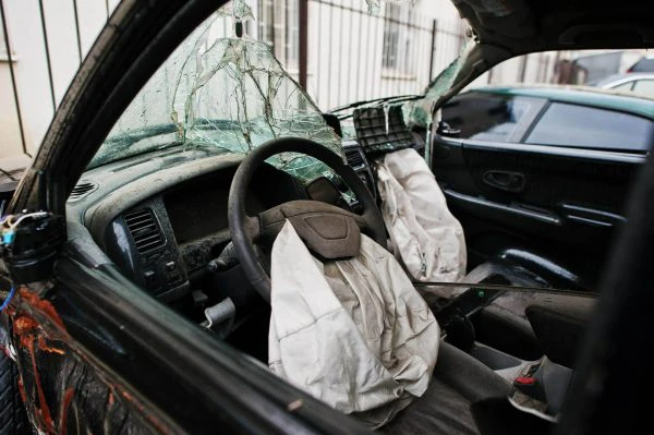 Seguridad activa y pasiva del vehículo: coche tras un accidente con la luna rota y el airbag fuera