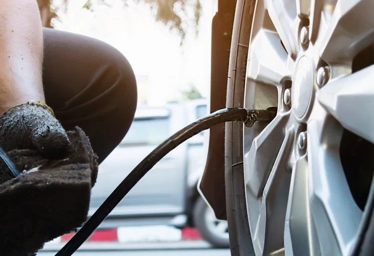 Trabajador/a con guantes revisando los neumáticos del vehículo