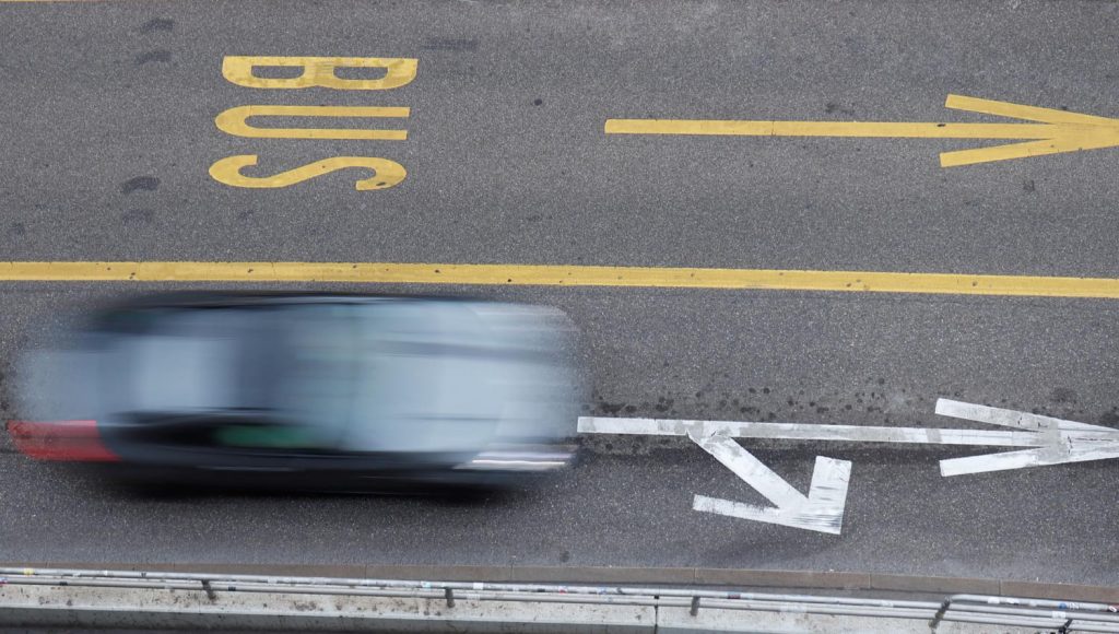 Vehículo en movimiento sobre un carril marcado como "BUS", capturado desde arriba. Explicativo sobre uso de carriles BUS-VAO y normativas - Carglass.