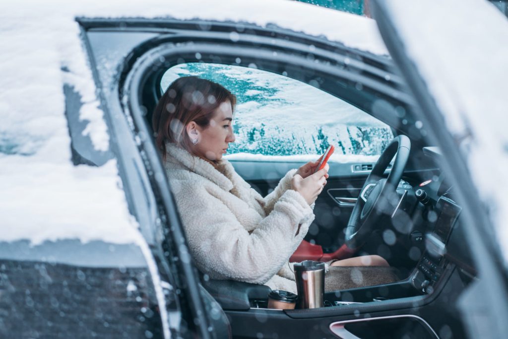Mujer en interior de coche cubierto de nieve aprendiendo como conducir con carreteras heladas - Carglass.