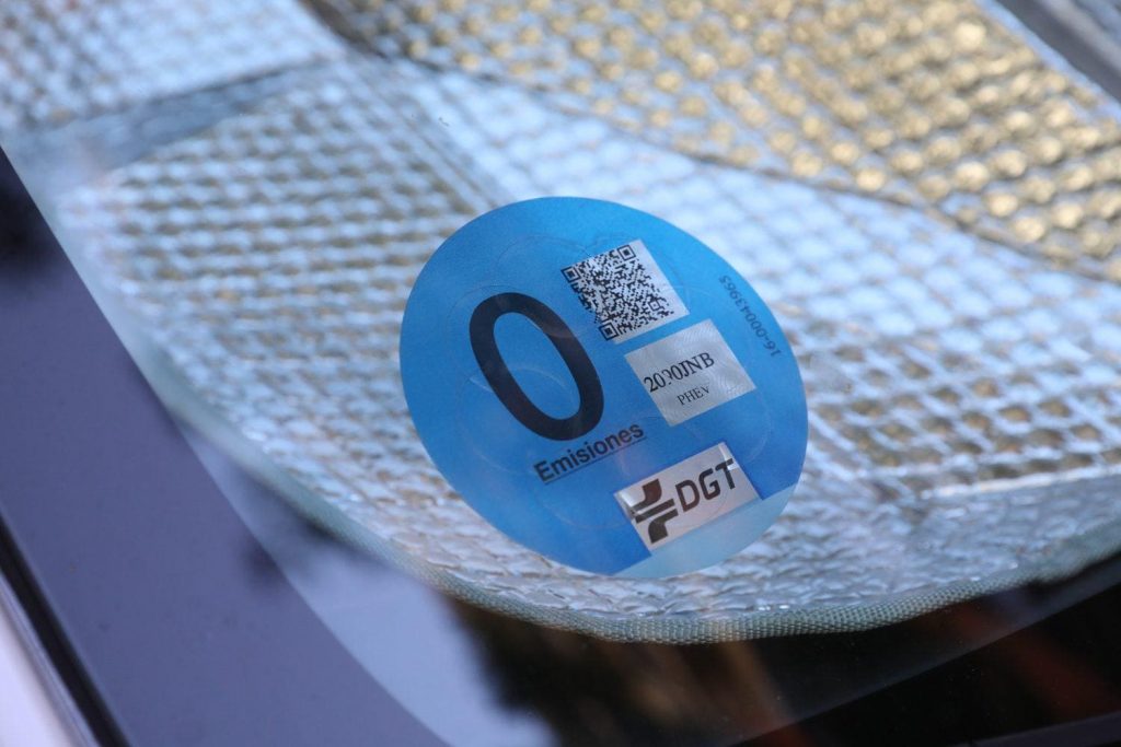 Etiqueta medioambiental azul de la DGT para vehículos de cero emisiones, adherida al parabrisas, destacando el compromiso ecológico. Etiqueta medioambiental DGT Cero - Carglass.