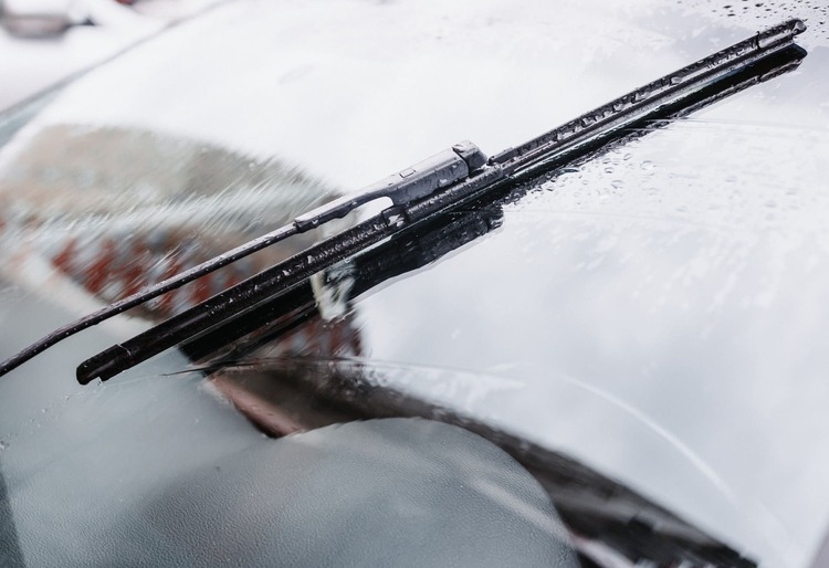 Primer plano de un limpiaparabrisas con gotas de agua sobre el cristal del coche, reflejando la lluvia reciente - Carglass.