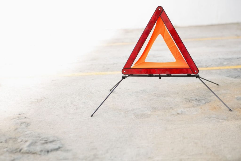Primer plano de un triángulo de emergencia desplegado sobre el asfalto, señalizando una posible avería - Carglass.
