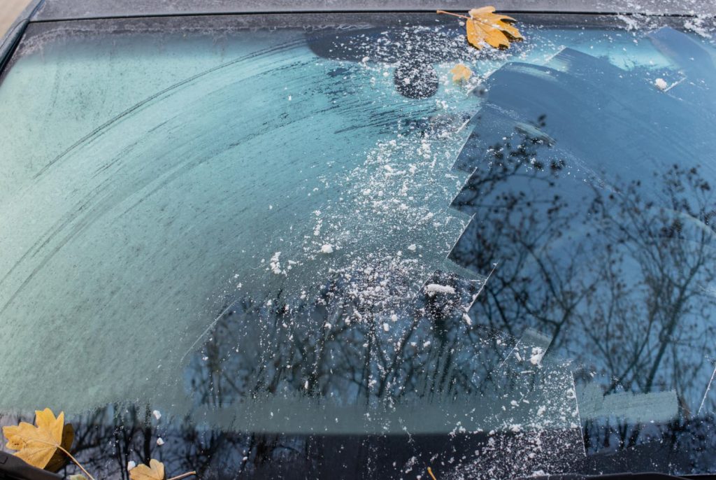 Parabrisas con escarcha parcialmente limpia, mostrando los peligros de mala visibilidad en cristales por hielo en invierno - Carglass.