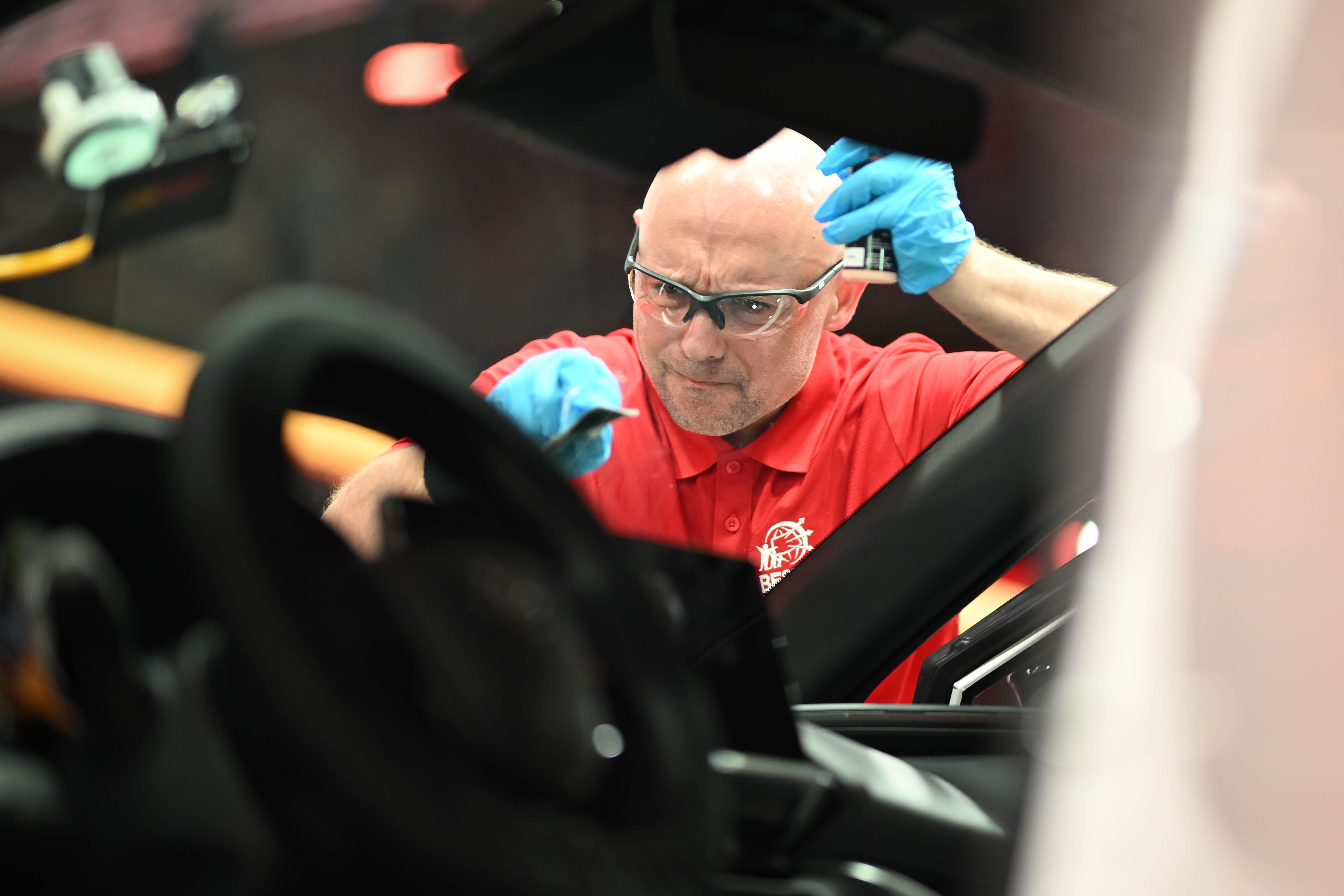 Best of Belron: personas mirando como un técnico cambia el parabrisas