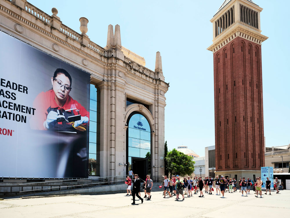 Competición Best of Belron en Barcelona: calle con personas pasando por en frente de un cartel publicitario de carglass