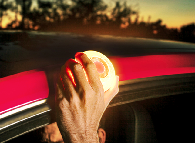 Luz de emergencia help flash: foto en primer plano de una mano colocando la luz de emergencia de la dgt encima del coche